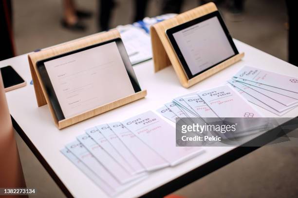テーブルの会議用にチェックインするためのビジネス会議カードとデジタルタブレット - パンフレット ストックフォトと画像