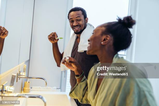 happy couple brushing teeth in bathroom - koppel toilet stockfoto's en -beelden