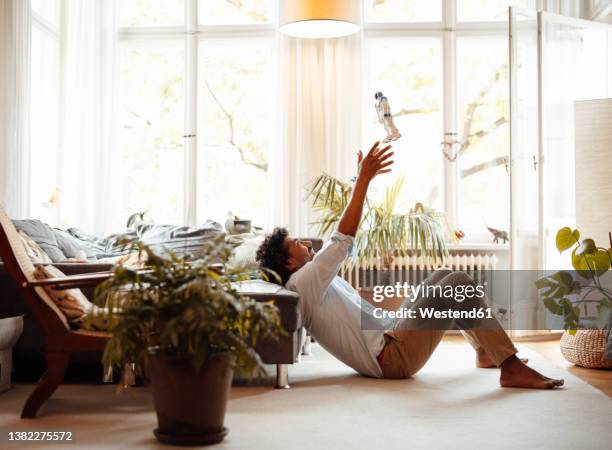 happy man catching robot toy sitting by sofa in living room - catching stock pictures, royalty-free photos & images