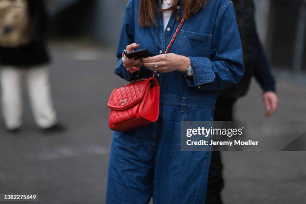 Fashion Week guest seen wearing a denim overall, white top and a red Chanel handbag on March 03, 2022 in Paris, France.