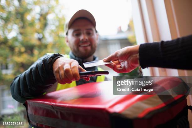 customer paying delivery man with contactless card at front door - debit cards credit cards accepted stock pictures, royalty-free photos & images