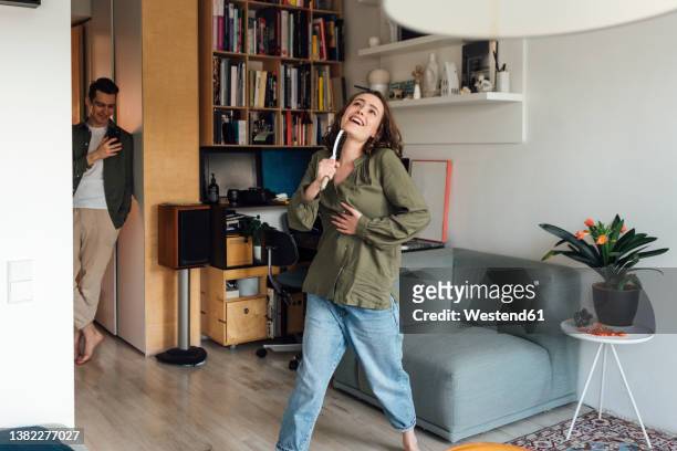 young man photographing woman singing in living room at home - cantar - fotografias e filmes do acervo