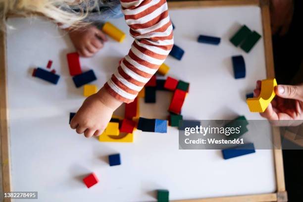 father and son playing with toy blocks at home - kid hand raised stock pictures, royalty-free photos & images