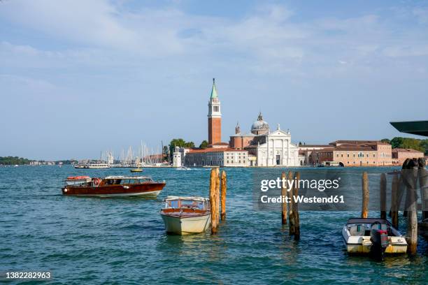 italy, veneto, venice, motorboats moored in marina with san giorgio maggiore island in background - venetian lagoon stock pictures, royalty-free photos & images