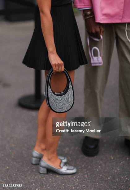 Fashion Week guest seen wearing a black skirt, a black rhinestones Coperni handbag, silver black rhinestones Prada loafers // next to her: beige...