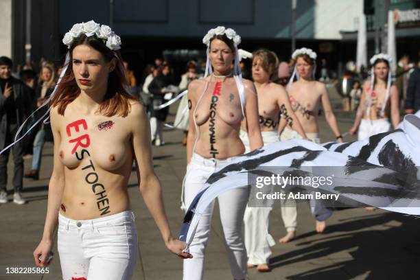 Members of the feminist activist group Femen, with the words "hit," "choked," "stabbed," "shot," "run over," and other means of murder written on...