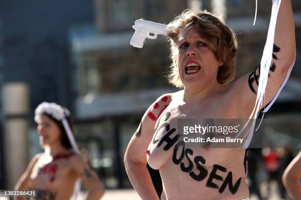 Members of the feminist activist group Femen, with the words "hit," "choked," "stabbed," "shot," "run over," and other means of murder written on...