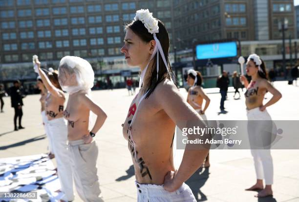 Members of the feminist activist group Femen, with the words "hit," "choked," "stabbed," "shot," "run over," and other means of murder written on...