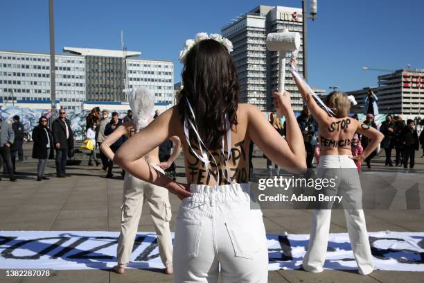 Members of the feminist activist group Femen, with the words "hit," "choked," "stabbed," "shot," "run over," and other means of murder written on...