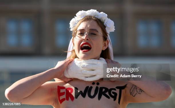 Member of the feminist activist group Femen, with the word "choked" written on her body, participates in a demonstration against femicide and...