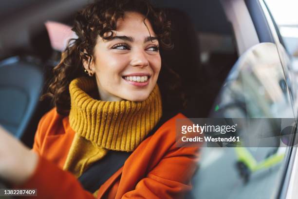 smiling woman looking through window of car - car top view foto e immagini stock