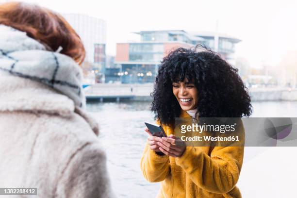 happy woman using smart phone in front of friend - urban areas　water front stockfoto's en -beelden