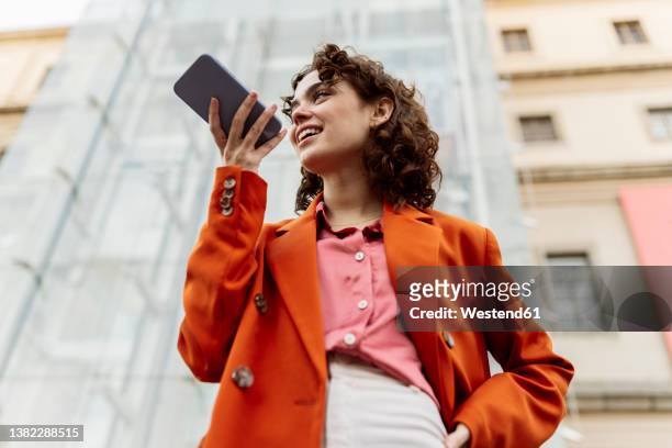 young woman sending voicemail through smart phone in city - speech recognition stock pictures, royalty-free photos & images