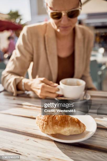 woman having coffee at sidewalk cafe on sunny day - languedoc rousillon stock pictures, royalty-free photos & images