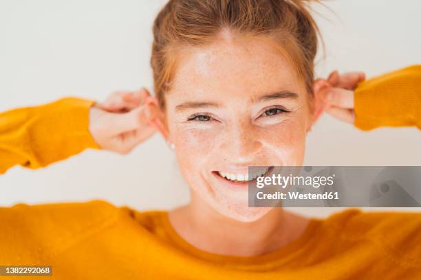 happy woman pulling ears in studio - human ear stockfoto's en -beelden