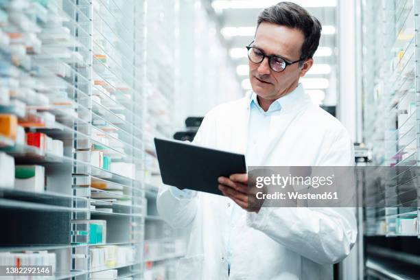 pharmacist with tablet pc taking inventory in storage room - apothekerberuf stock-fotos und bilder