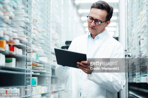 pharmacist with tablet pc taking inventory in storage room - pharmacy imagens e fotografias de stock