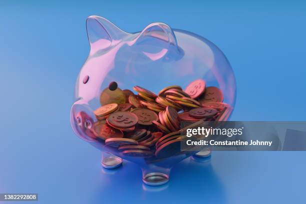 see through transparent glass piggy bank with coins on blue background - busta paga foto e immagini stock