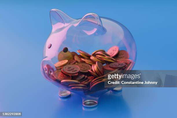 see through transparent glass piggy bank with coins on blue background - debt collector stock pictures, royalty-free photos & images