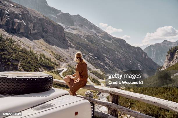 tourist sitting on wooden railing by off-road vehicle, stelvio pass, south tyrol, italy - stelvio pass stock pictures, royalty-free photos & images