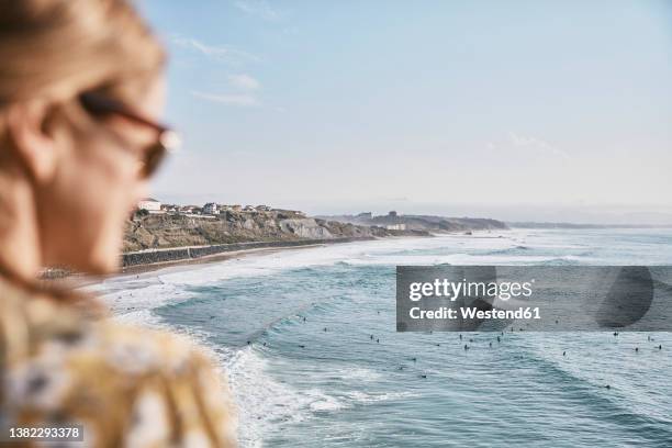 woman looking at sea on sunny day - biarritz stockfoto's en -beelden