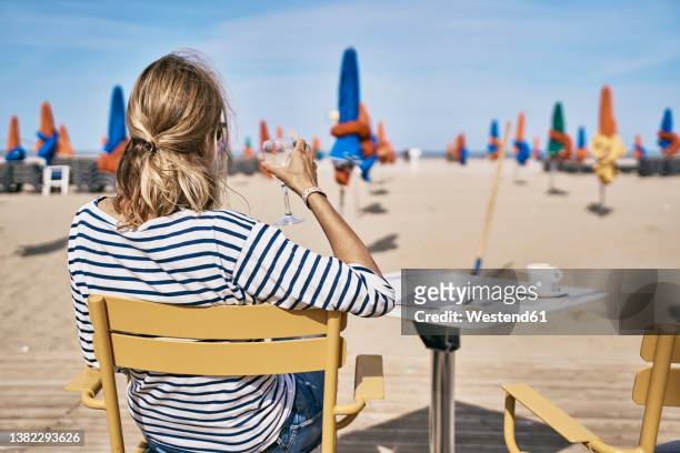 woman with wineglass sitting on chair at vacation - deauville beach stock pictures, royalty-free photos & images