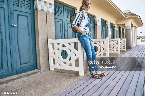 woman standing in front of beach huts at vacation - deauville beach stock pictures, royalty-free photos & images