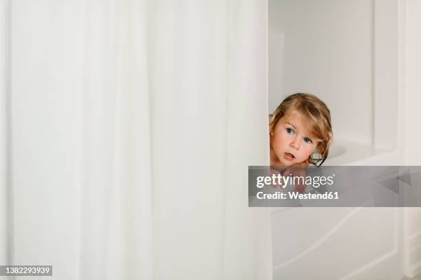 cute girl peeking in bathtub - rideau de douche photos et images de collection