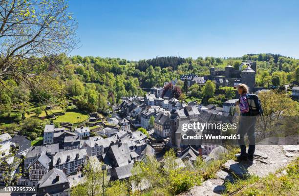germany, north rhine-westphalia, monschau, female hiker admiring view of medieval town in spring - germany castle stock-fotos und bilder