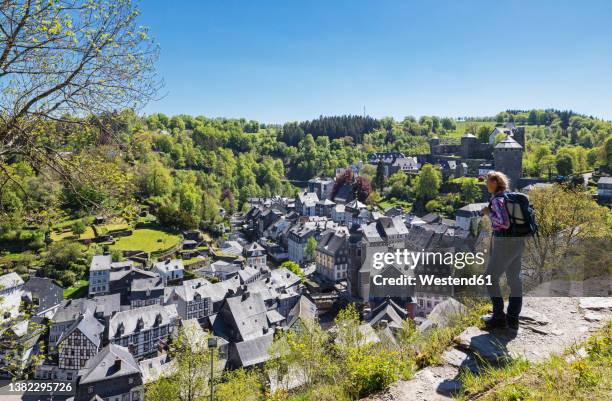 germany, north rhine-westphalia, monschau, female hiker admiring view of medieval town in spring - eifel stock pictures, royalty-free photos & images