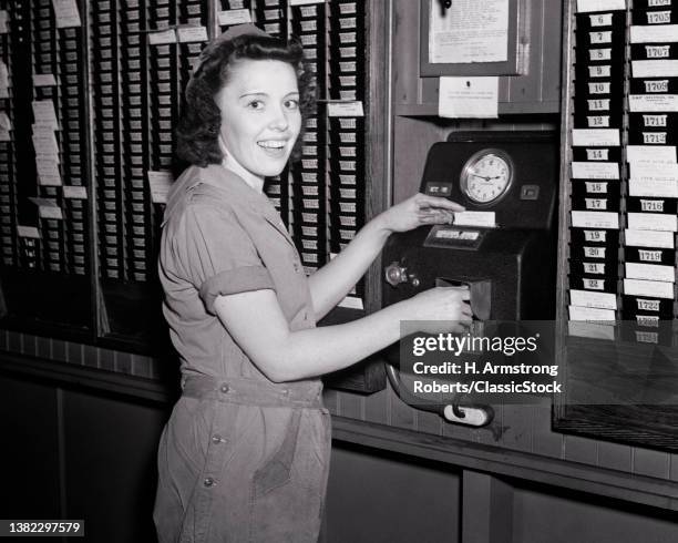 1940s World War 2 Woman Defense Worker In Roller Bearing Company Punching In Time Clock Smiling Looking At Camera.