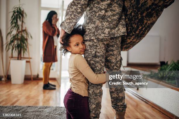 father soldier leaving home to go to war and serve his  country. his wife is crying and his daughter holds his leg, and begs him to stay home and not to go - soldier praying stockfoto's en -beelden