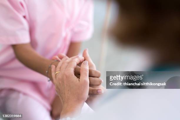 close up of doctor holding patient's hand, encourage patients to sitting on the bed in hospital.helping hand concept. - holding hands close up stock-fotos und bilder