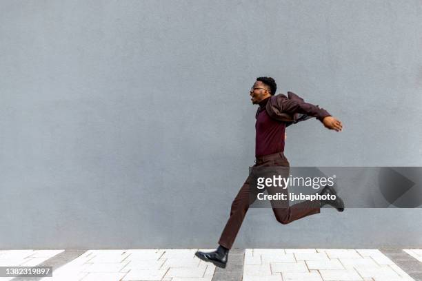 ein männlicher geschäftsmann springt in der stadt - running midair stock-fotos und bilder