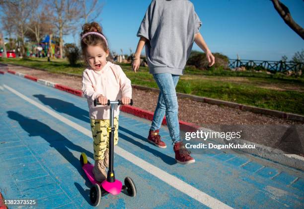 my mom teaches me to ride a scooter. - girl riding scooter stock pictures, royalty-free photos & images