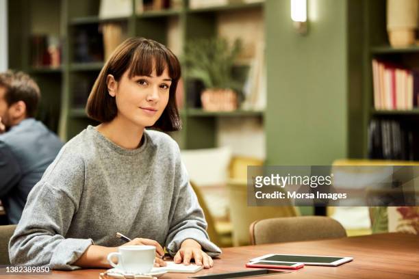businesswoman working at desk in creative office - solo una donna giovane foto e immagini stock
