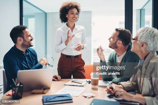 smiling businesswoman talking to her coworkers - new business opportunities stock pictures, royalty-free photos & images