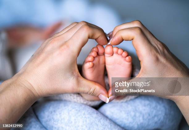 newborn baby's feet on female heart shaped hands - little feet stock pictures, royalty-free photos & images