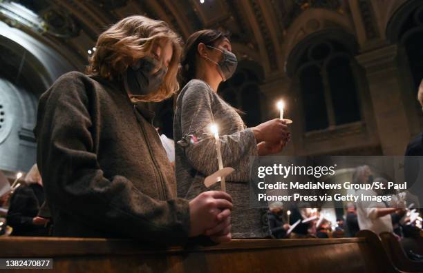 People hold candles as they pray for peace in Ukraine at the Basilica of Saint Mary in Minneapolis, Minn. On Sunday evening, March 6, 2022. The...