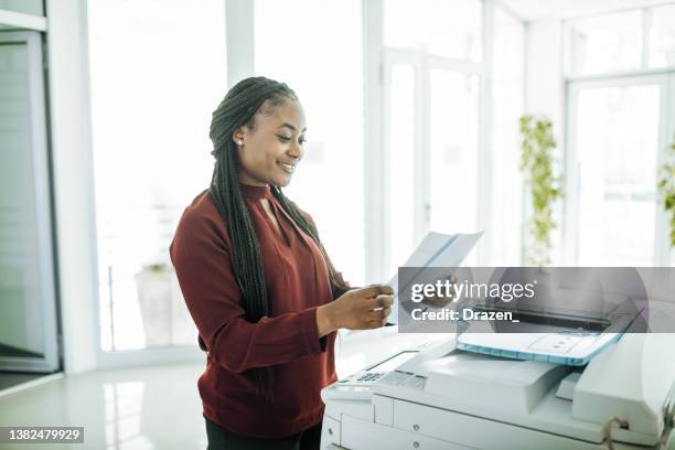 african-american businesswoman working in office after reopening, using photo copier - fotokopieerapparaat stockfoto's en -beelden