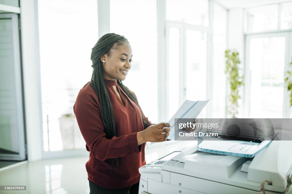 African-American businesswoman working in office after reopening, using photo copier