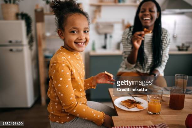 portrait of girl having breakfast with mother at dining table - plate eating table imagens e fotografias de stock