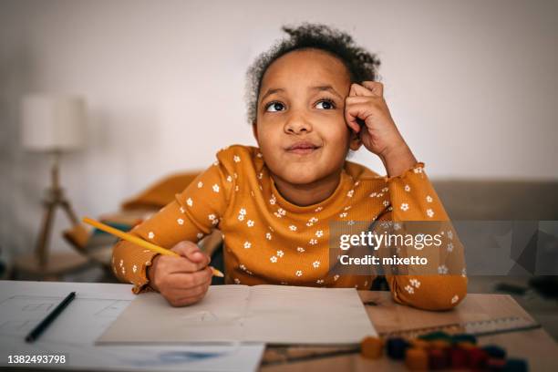 bored girl thinking while writing homework at home - beschrijvende begrippen stockfoto's en -beelden