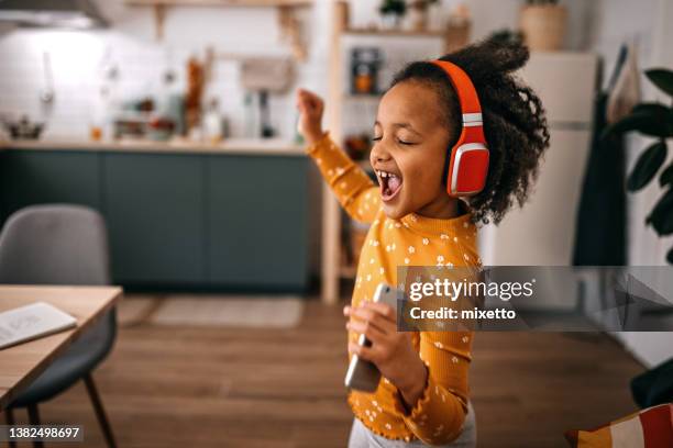 cheerful girl listening music and dancing at home - girl singing imagens e fotografias de stock