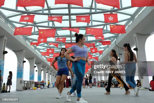 Woman dance under flags of Hong Kong and China at Central Ferry Piers in Hong Kong on July 2 a day after the city marked the 26th anniversary of its...