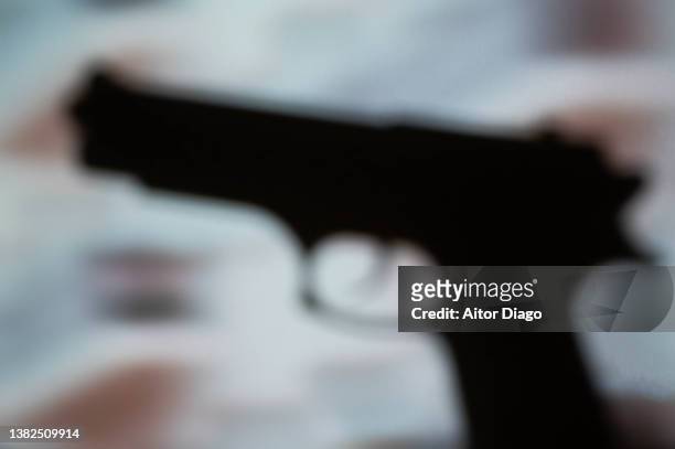 silhouette of a gun in in movement. war concept. - pistolenschießen stock-fotos und bilder