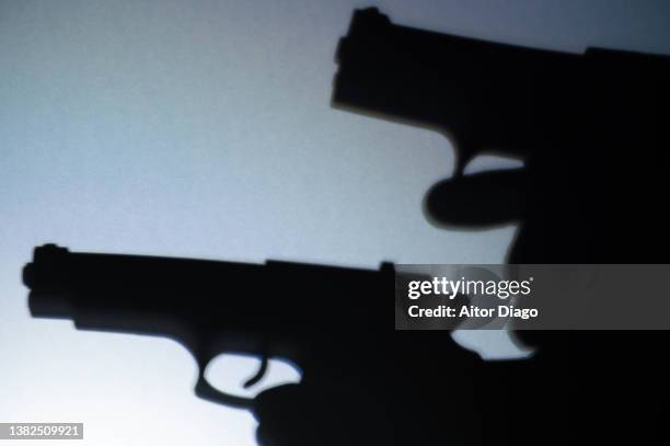 silhouette two persons with guns ready to shoot. war concept. - pistolenschießen stock-fotos und bilder
