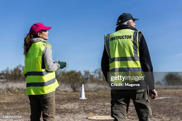 drone instructor and his student controlling drone by remote control both looking at drone on air - drone pilot stock pictures, royalty-free photos & images