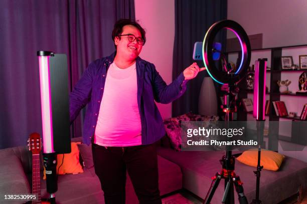 overweight young man filming videos at home and talking to camera set on ring light - male influencer stock pictures, royalty-free photos & images