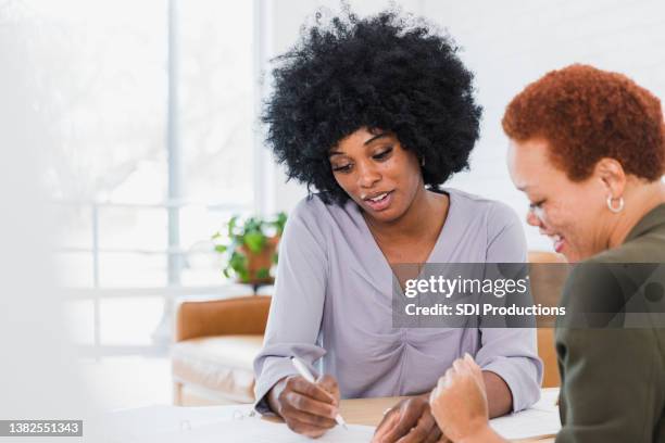 young adult female real estate agent explains contract to client - ethnic millennial real estate stockfoto's en -beelden